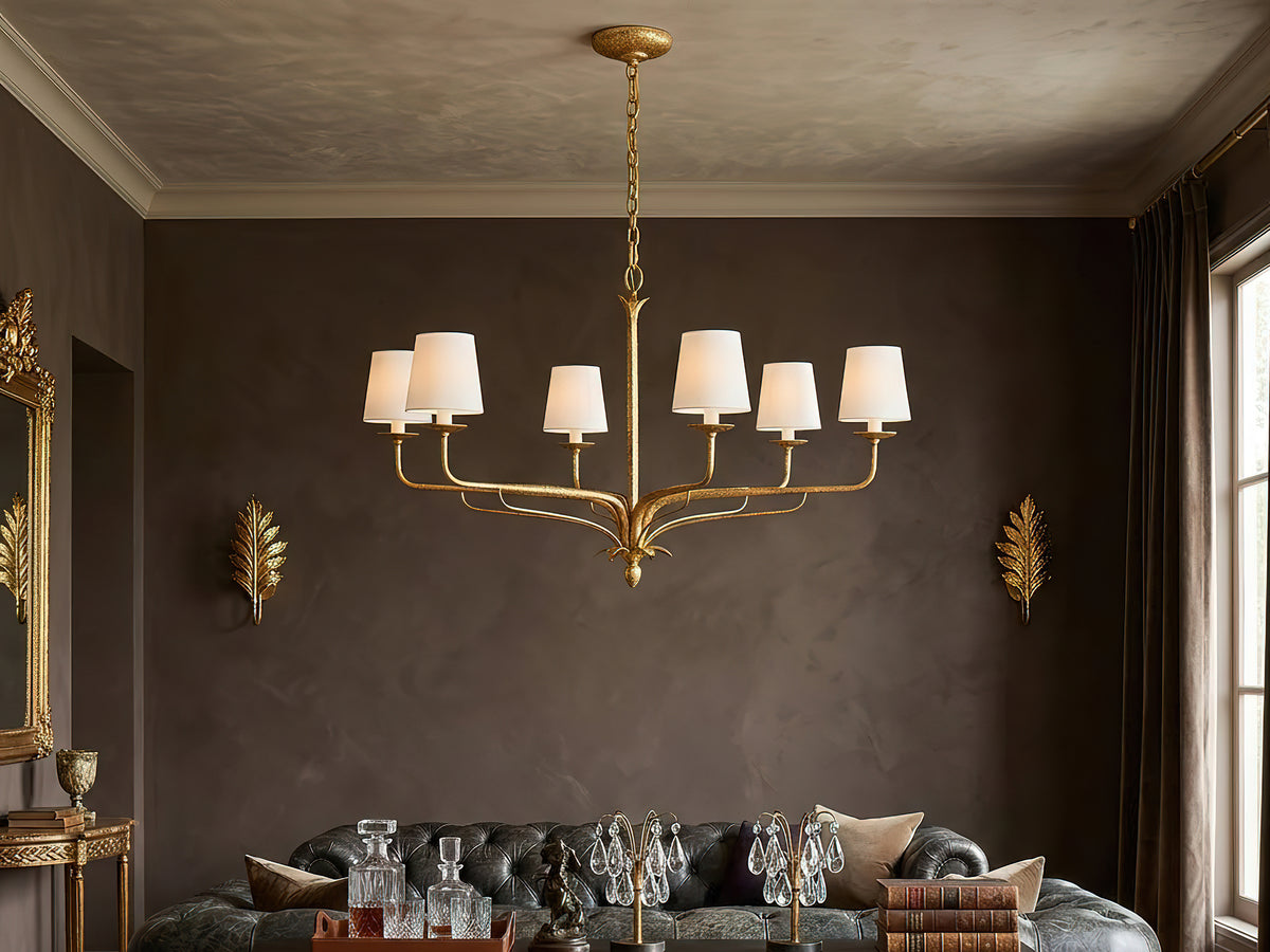Brass chandelier with white shades in a warm, dark room